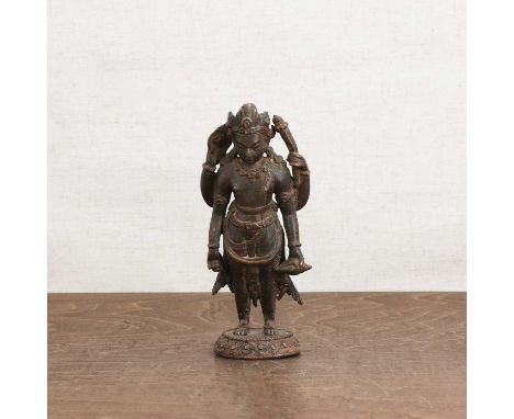 A Nepalese bronze bodhisattva,standing on a lotus pedestal, each one of four hands holding a Buddhist attribute, 18cm highCon