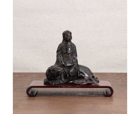 A Japanese bronze figure,20th century, of Kwannon seated on a Buddhist lion, wearing a long robe with a scroll in his hands,1