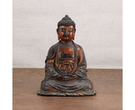 A Chinese gilt-lacquered bronze Buddha,Ming dynasty (1368-1644), wearing a long robe, seated cross-legged with his hands rest