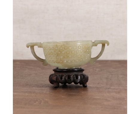 A Chinese jade two-handled cup,Ming dynasty (1368-1644), the rounded sides flanked by two stylised handles, rising from a spl