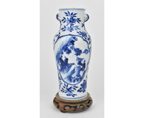 A late Qing dynasty blue and white porcelain baluster vase, circa 1900, with central cartouche depicting two men in a natural