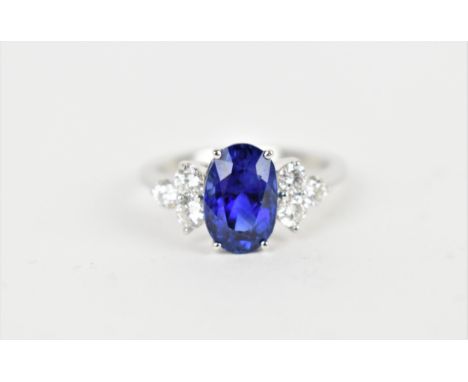 An 18ct white gold, diamond and sapphire dress ring, with central oval cut sapphire in a four claw setting, flanked with thre