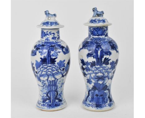 A near pair of late Qing dynasty blue and white porcelain lidded baluster vases, decorated with birds in a true above a large