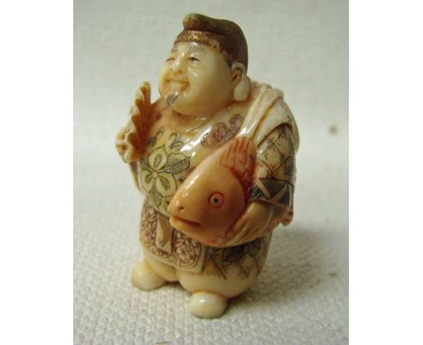 A Japanese ivory Netsuke, late 19th/early 20th century, a robed mythological character holding a fan in one hand and a fish u