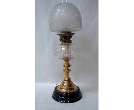 A late Victorian brass oil lamp with compressed and facetted glass oil reservoir, etched glass shade on a knopped brass colum