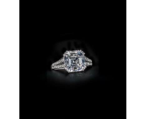 A diamond solitaire ring, the Asscher cut diamond weighs 5.47cts and is set within millegrain-set diamond shoulders in carved