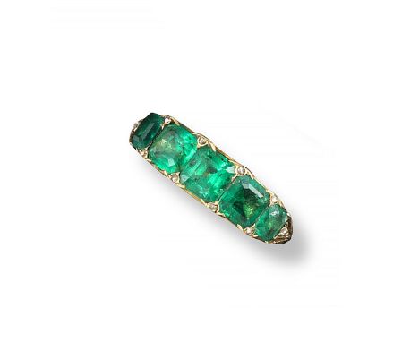 A late Victorian emerald five stone ring, the five graduated emerald-cut emeralds, with diamond pointers set in scroll-carved