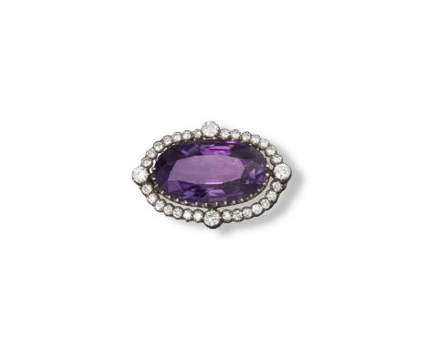 An amethyst and diamond brooch, set with a long oval-shaped amethyst within a border of circular cut diamonds in silver and g