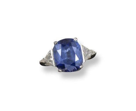 A sapphire and diamond three stone ring, the oval-shaped sapphire is set with two triangular cut shoulder diamonds in white g