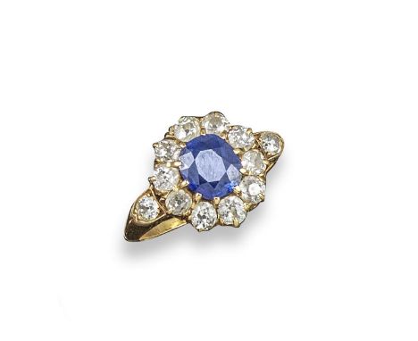 A sapphire and diamond cluster ring, the oval-shaped sapphire is set within a surround of old cushion-shaped diamonds in yell