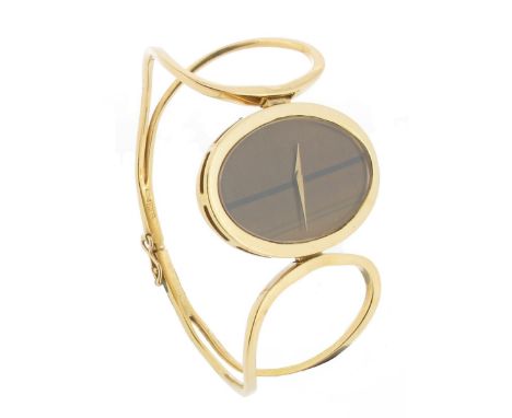 A lady's gold bangle wristwatch by Chopard, the tonneau-shaped signed tiger's eye dial within yellow gold border and yellow g