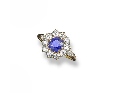 A sapphire and diamond cluster ring, the oval-shaped sapphire is set within a surround of circular-cut diamonds in yellow gol