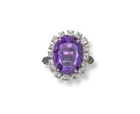 An amethyst and diamond set ring, the oval-shaped amethyst is set within a surround of circular-cut diamonds in white gold. S