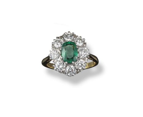 An emerald and diamond cluster ring, the emerald-cut emerald is set within a surround of eight circular-cut diamonds in plati