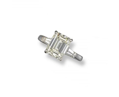 An emerald cut diamond solitaire ring, the diamond weighs 6.27cts and is set with two tapered baguette shoulder diamonds in p