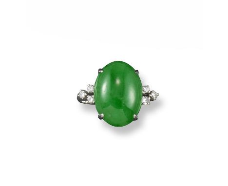 A jade and diamond ring, the oval shaped jadeite cabochon is set with three diamonds to each shoulder in platinum. Size N 1/2