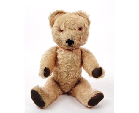 An early 20th century English mechanical teddy bear. Having mohair exterior, with orange eyes.