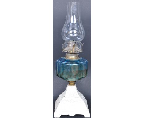 An early 20th century oil / paraffin lamp having a glass flue to the top, blue glass reservoir to the centre raised on a pain