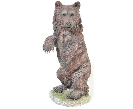 A large 20th century floor standing resin casting statue / figurine of a black bear being raised on a naturalistic plinth bas