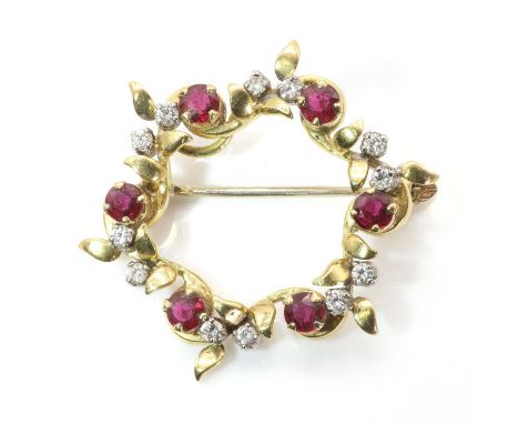 An 18ct gold ruby and diamond openwork brooch,the scrolling circular frame with foliate sprays accented with circular cut rub