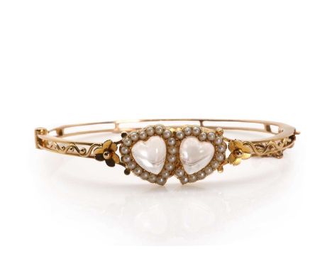A Victorian double heart moonstone and seed pearl bangle, with two cabochon moonstone hearts in overlapping borders of seed p