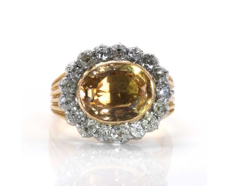 A foiled topaz and diamond oval cluster ring,  the oval cut apricot coloured topaz horizontally set in a millegrain edged col