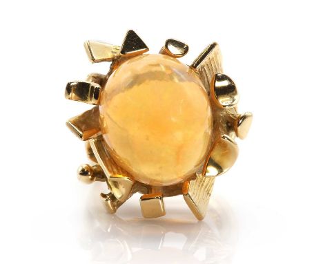 An abstract design fire opal ring, the deep oval cabochon fire opal is light orange in hue with good play of colour, principa