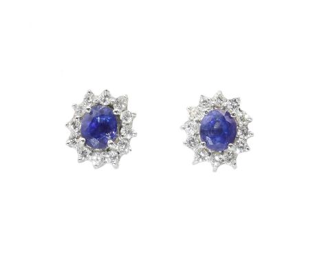 A pair of Continental sapphire and diamond oval cluster earrings,with an oval mixed cut sapphire, claw set to a border of bri