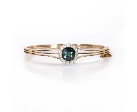 An early 20th century green sapphire and diamond cluster hinged bangle,a cushion cut bluish green sapphire claw set within a 