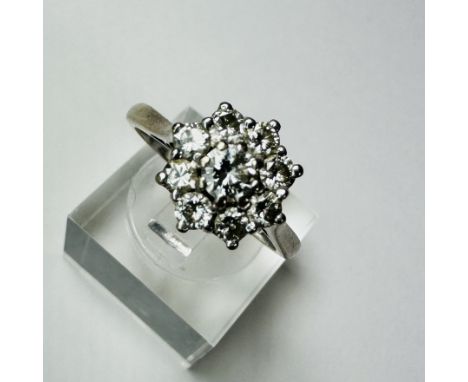 A diamond daisy ring. Set with nine round brilliant cut diamonds, the central stone an estimated 0.20 carats, the surrounding