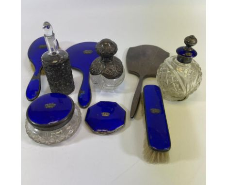 A silver and enamel six piece dressing set, two silver mounted bottles and a silver back mirror. Enamel is all chipped except