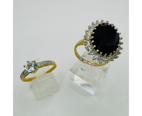 A pair of gold plated costume jewellery rings, one set with a large oval black stone, surrounded by white stones; the other a