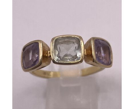 A prasiolite and amethyst 18ct yellow gold ring. Prasiolite (green quartz) central stone flanked by two light purple amethyst