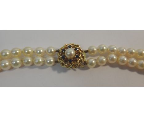 A two row necklace of uniform cultured pearls, on a gold, sapphire and cultured pearl set circular clasp, mounted with the si