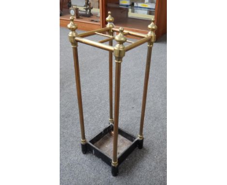 An Edwardian brass and cast iron four division stick stand of square section, with turned finials and an ebonised cast iron b