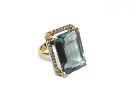 A gold, synthetic pale blue quartz and diamond set ring, claw set with the rectangular cut pale blue gem at the centre, withi