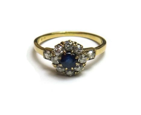 A gold, sapphire and diamond set cluster ring, claw set with the cushion shaped sapphire at the centre, in a surround of eigh