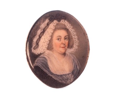 A gold mounted oval portrait miniature of a lady, with curly grey hair, wearing a white bonnet, converted for wear from a cla