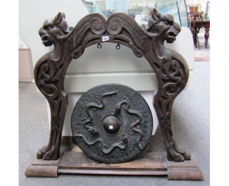 An ornate gong, the Sino-Tibetan bronze gong with high relief dragon decoration suspended from stand formed as an addorsed pa