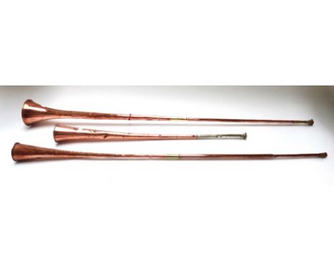 Four large copper hunting horns, 19th century, all with brass mounts (a.f), the longest 149cm (4).