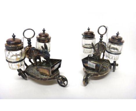 A pair of plated novelty cruets, each formed as a standing donkey feeding from a trough, the sides fitted with two glass cond