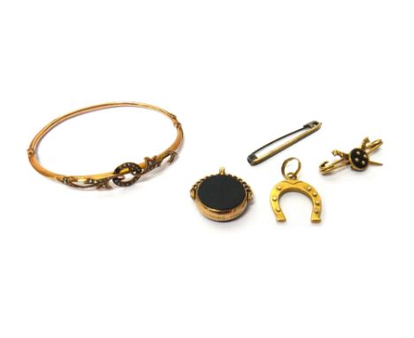 A gold and seed pearl set oval hinged bangle, the front with scrolling decoration, a gold pendant, designed as a horseshoe, d