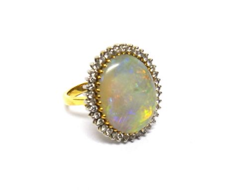 An 18ct gold, opal and diamond set ring, claw set with the large oval opal at the centre, within a surround of small circular