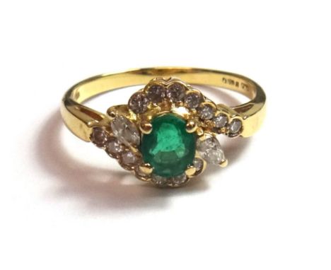 An 18ct gold, emerald and diamond set ring, claw set with the oval cut emerald at the centre, between two marquise shaped dia