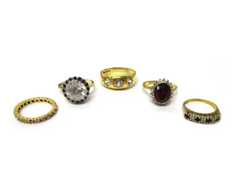 A gold, garnet and diamond set oval cluster ring, claw set with the oval cut garnet at the centre, within a surround of circu