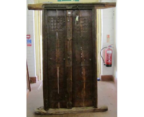 An Omani carved hardwood door and frame surround, with chip carved geometric circles and chevrons panel decoration and hard w