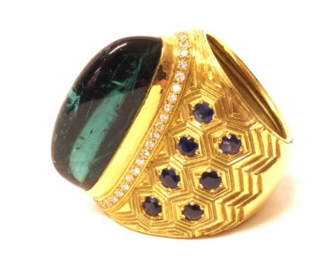 A gold, sapphire, diamond and blue green tourmaline set dress ring, mounted with the cabochon tourmaline at the centre, withi