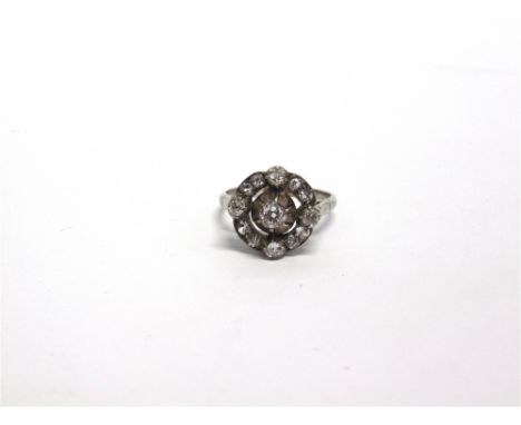 A LATE VICTORIAN DIAMOND CLUSTER RING  in an unmarked white metal, the central silver collet set old brilliant cut of approxi