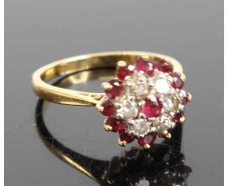 An 18ct gold ruby and diamond circular cluster ring, featuring a centre round ruby within a border of six round brilliant cut