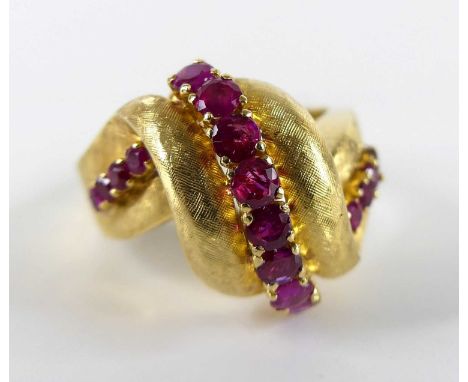 A yellow metal ruby multi-stone scrollwork ring, featuring a centre band of eight round cut rubies with four rubies in each s